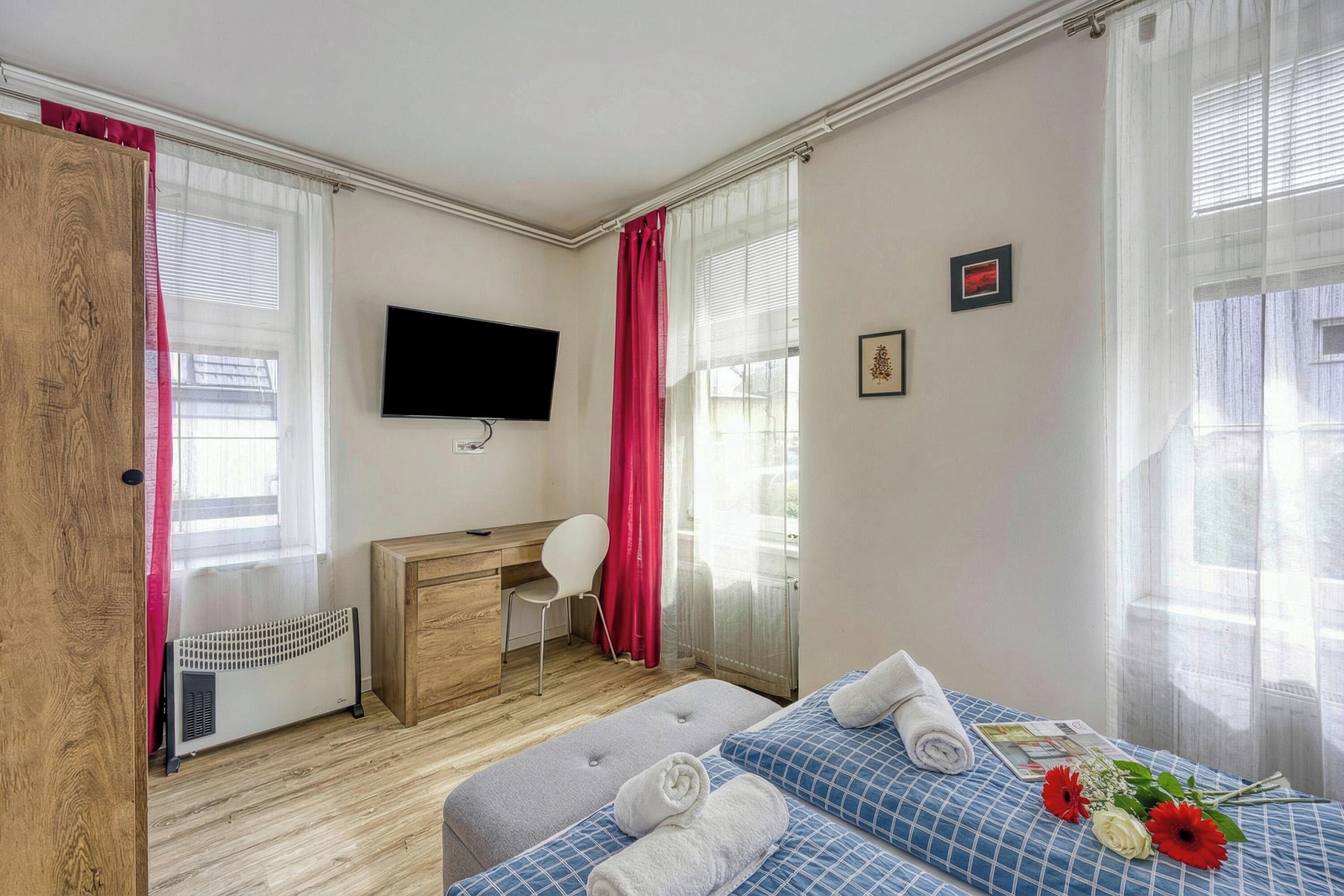 Een hotelkamer met een bed, een bureau, een stoel, een televisie en een raam met gordijnen.