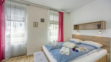 Ein Schlafzimmer mit einem hölzernen Kopfteil, einem Bett mit blau-weißer Karomattraze, einem Nachttisch und einem kleinen Regal über dem Bett.