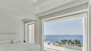 A modern bedroom with a large bed, a view of the sea, and a pool. - OLYN VILLAS (Nikiti)