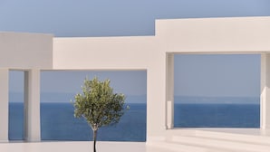 A modern interior with a view of the sea, featuring a minimalist design with white walls and large windows. - OLYN VILLAS (Nikiti)