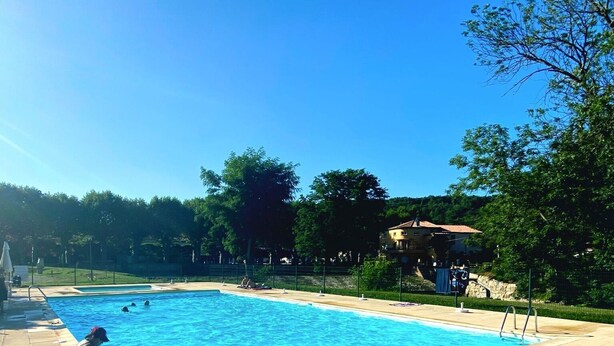 Una piscina rectangular con agua azul cristalina, rodeada por una terraza con baldosas.