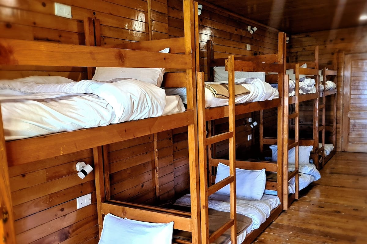 A row of wooden bunk beds in a cabin-style room with wooden walls and floors.