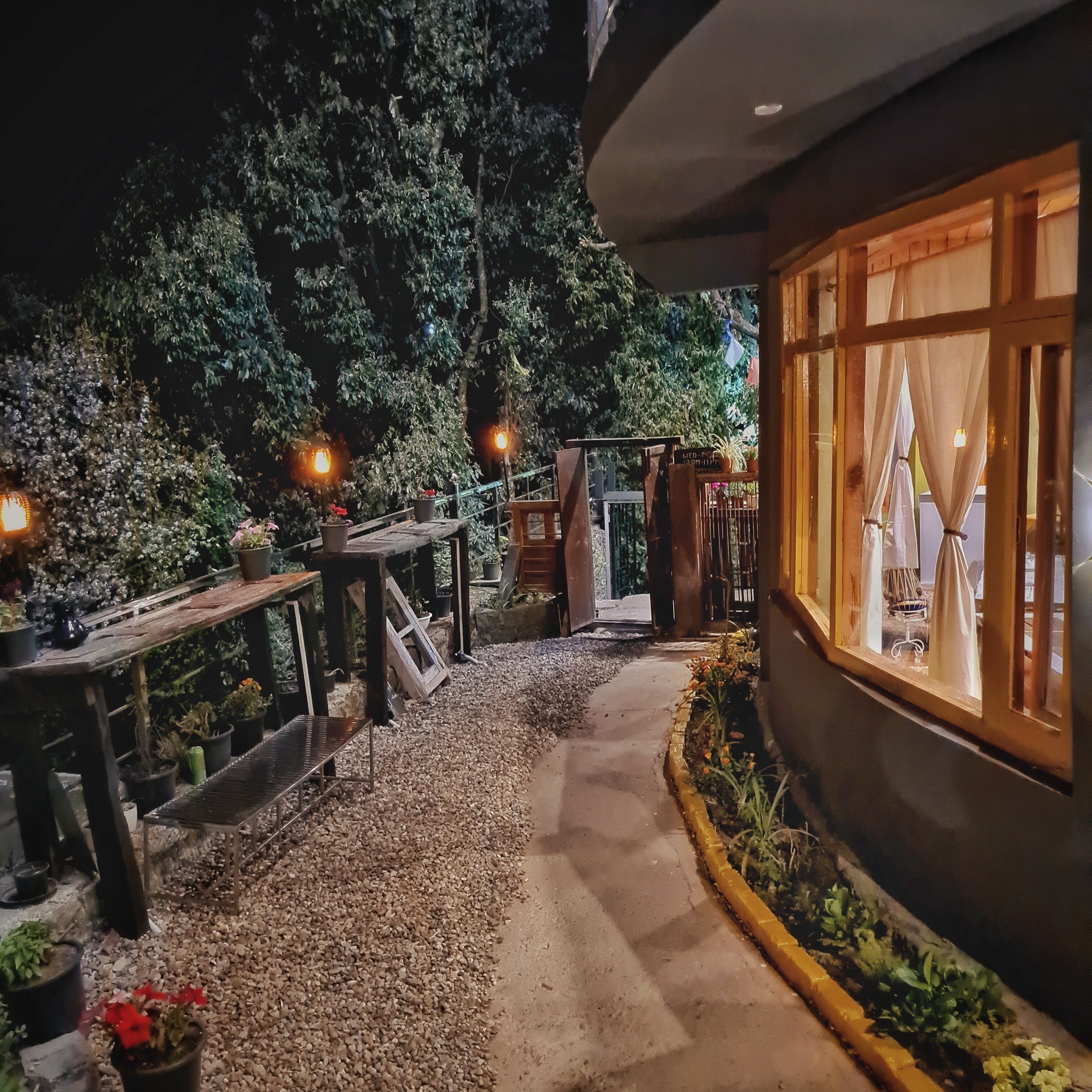 A pathway leading to a building with a wooden deck and potted plants.