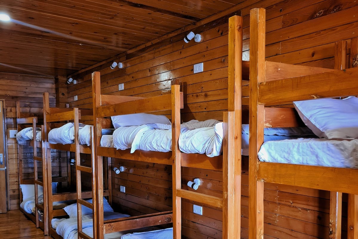 A row of bunk beds in a wooden cabin-style room with a wooden floor and walls.