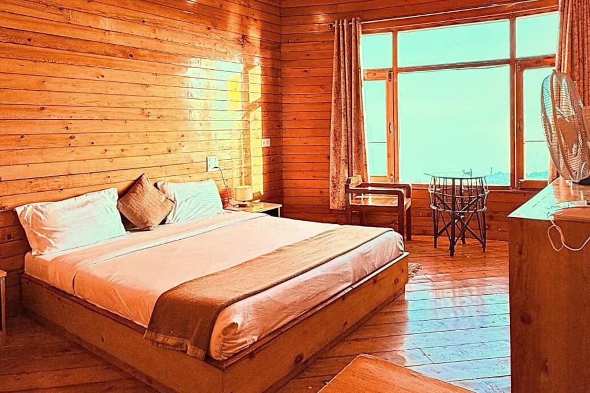 A wooden cabin room with a bed, a small table, and a chair.