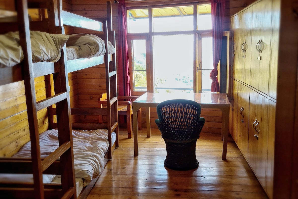 A wooden cabin with bunk beds, a table, and a chair.