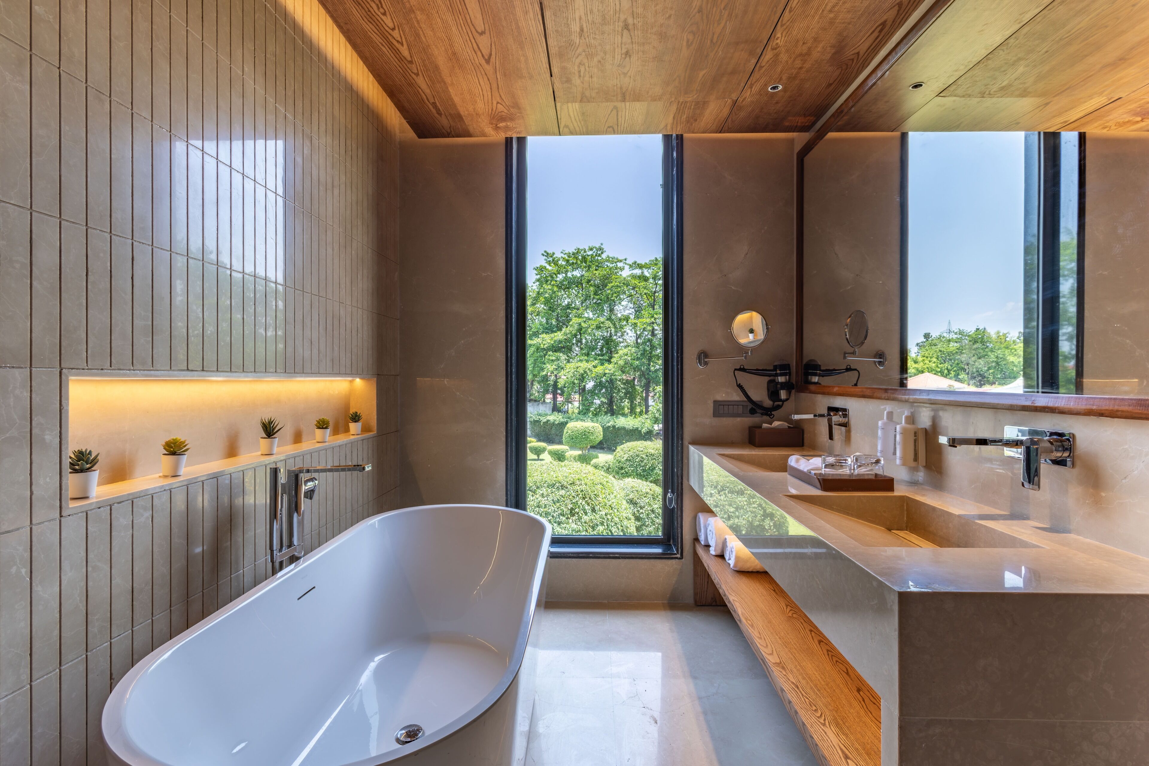 Un baño moderno con una bañera independiente, un ventanal grande y un techo de madera.