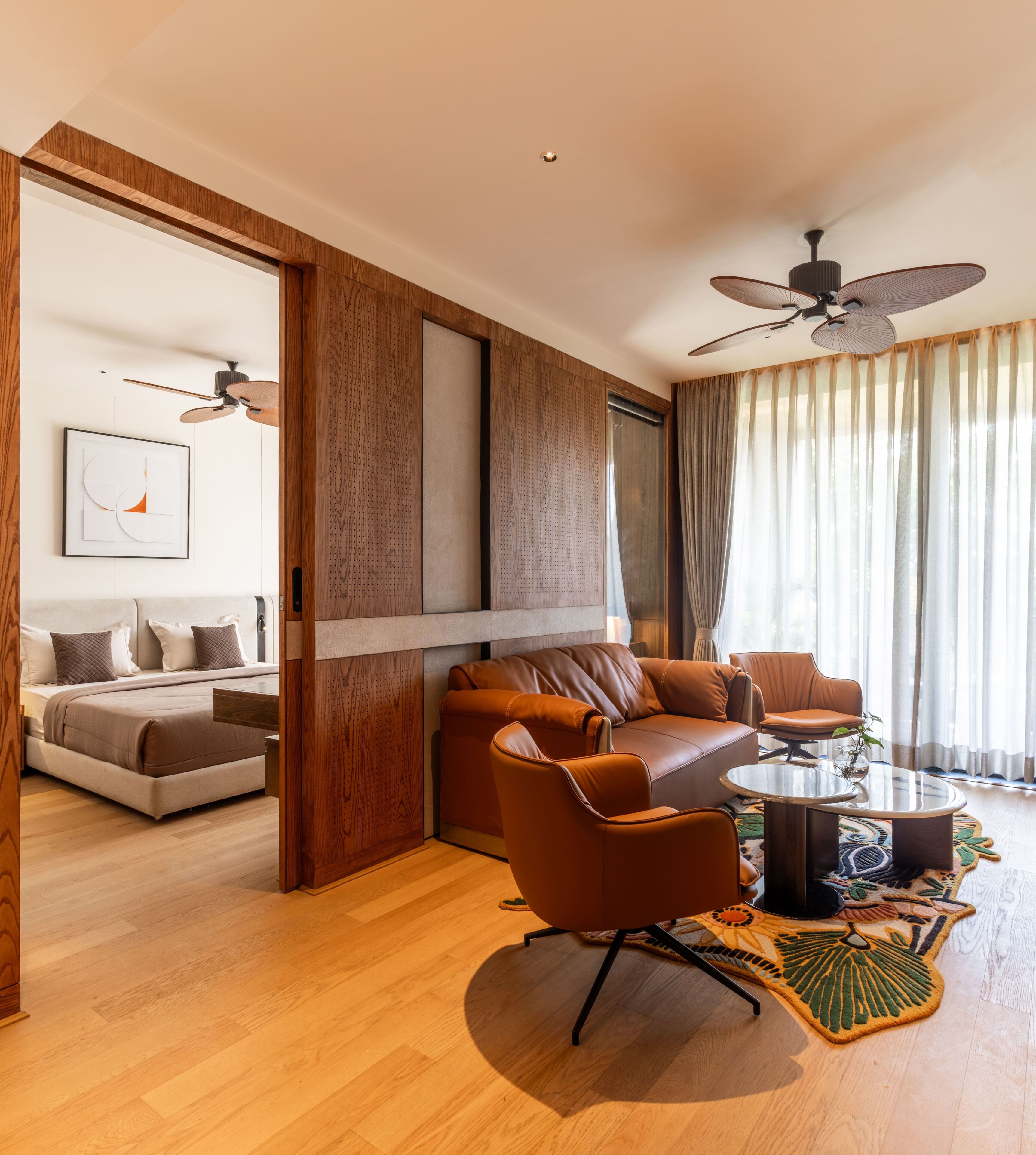 A modern living room with a sofa, chairs, a coffee table, and a ceiling fan.