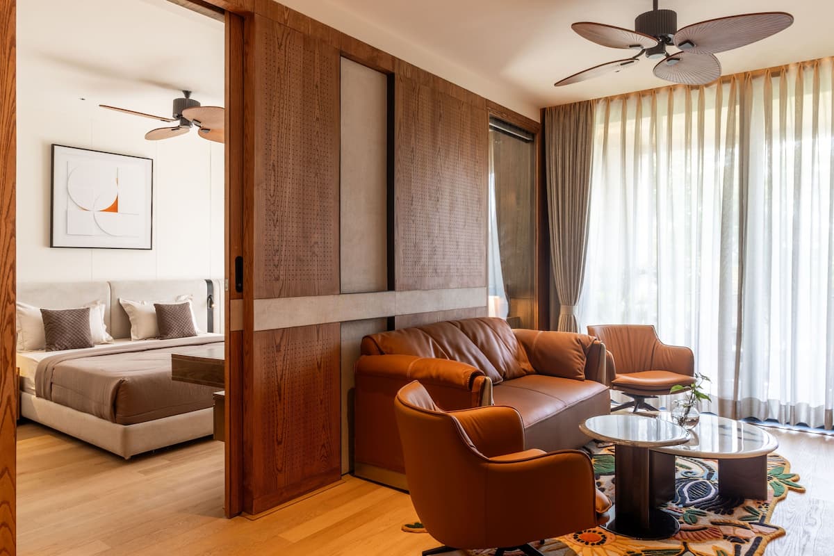 Un salon moderne avec un canapé, des fauteuils, une table basse et un ventilateur de plafond.