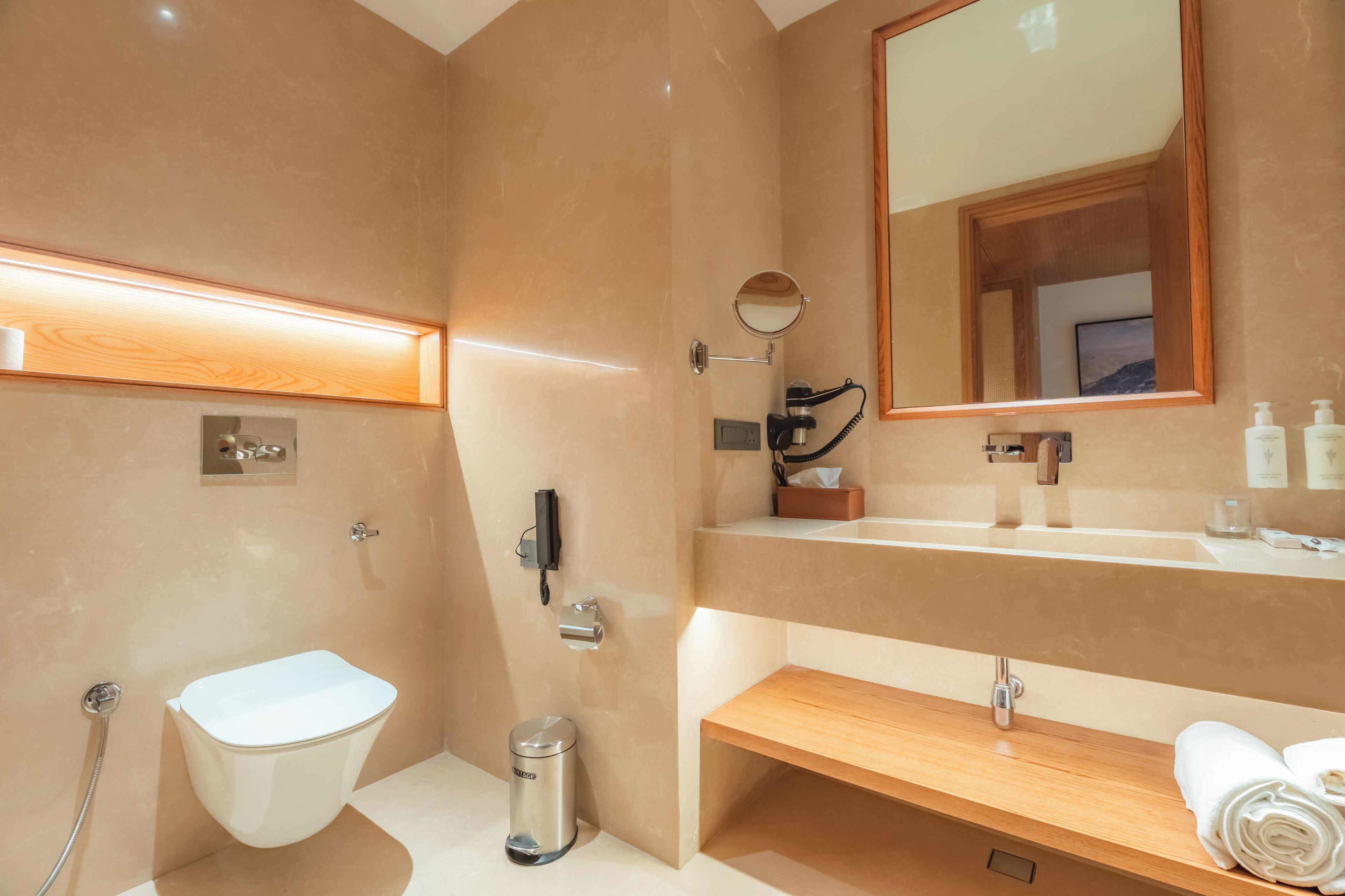 Un baño moderno con inodoro, bidé, tocador, espejo y toallero.