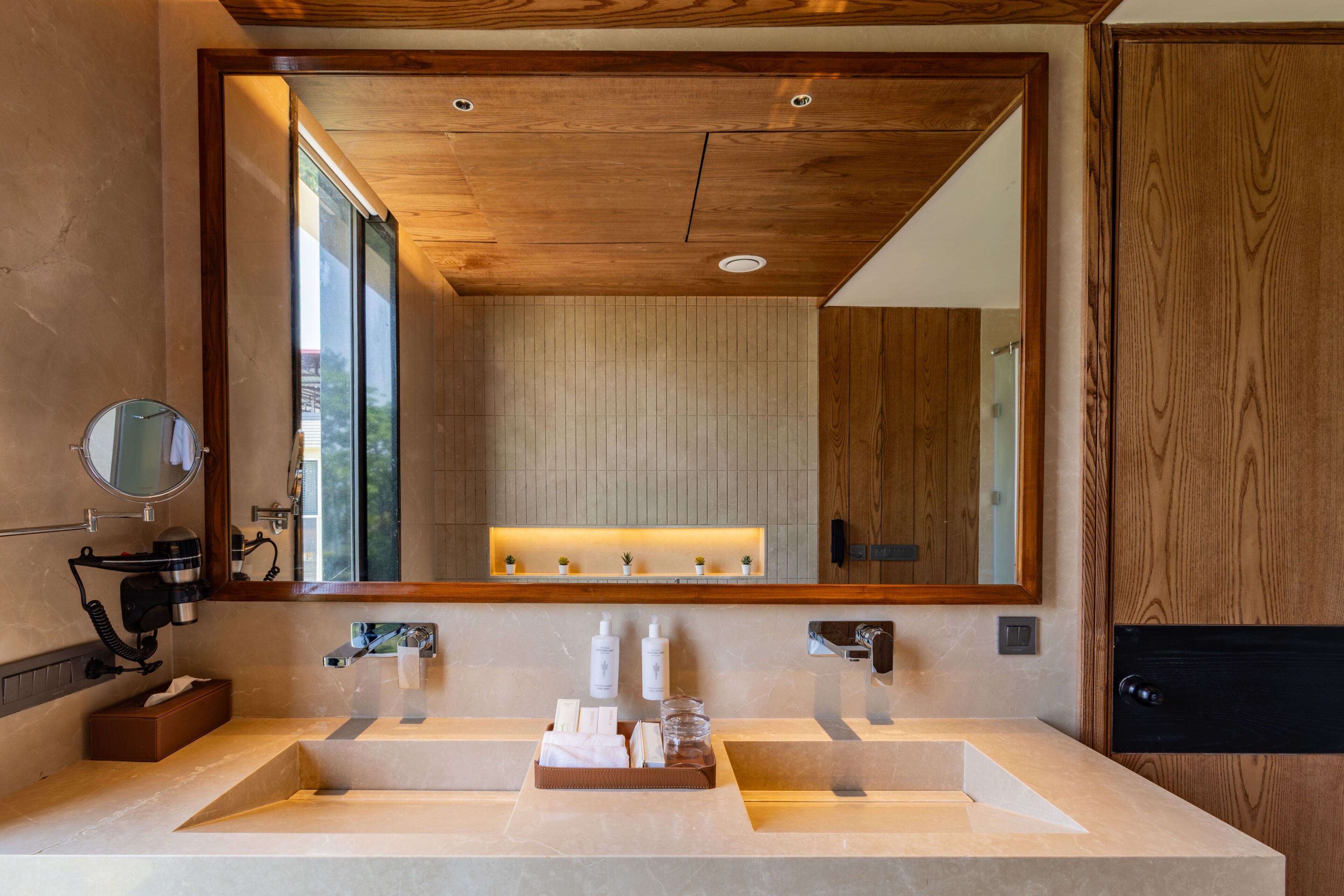 A modern bathroom with a large mirror, wooden ceiling, and a vanity with two sinks.