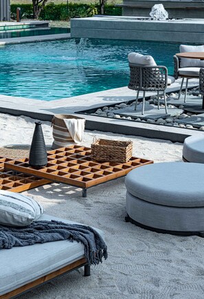 Ein Poolbereich mit Holztisch, Korbwannen und einer Bank.