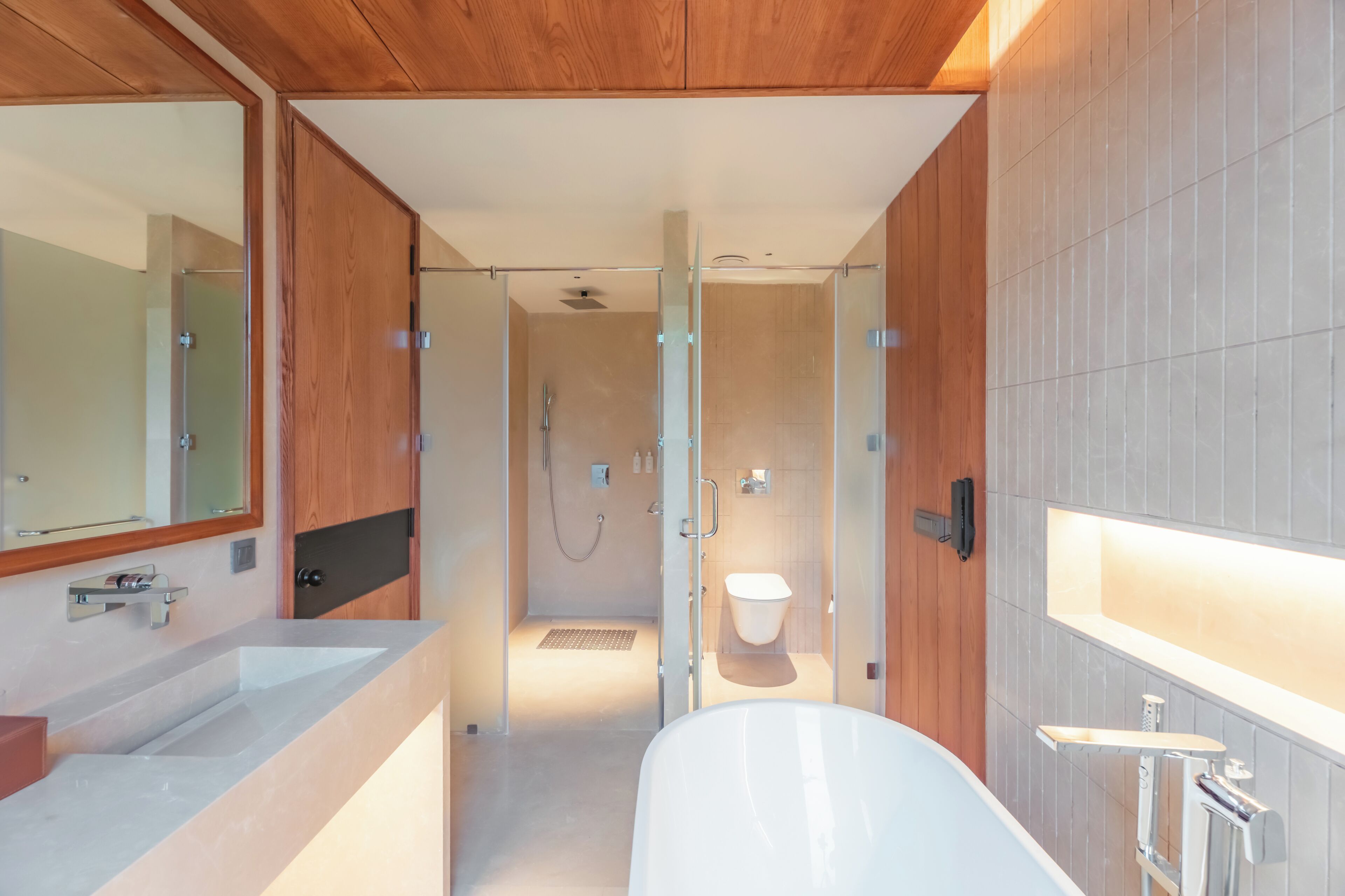 Un baño moderno con ducha de vidrio, una bañera blanca y un espejo grande.
