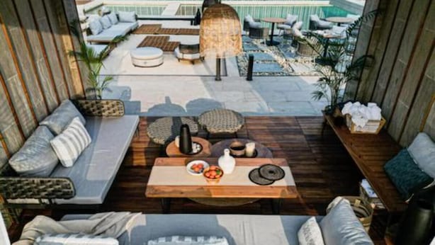 Un espace de détente aménagé sur le toit, avec des sièges et une table, d’où l’on a vue sur une piscine.