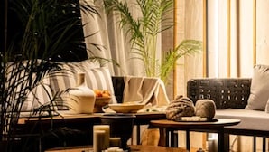 Un salon chaleureux avec un canapé, une table basse et une petite table d’appoint sur laquelle sont posées des bougies et des en-cas.