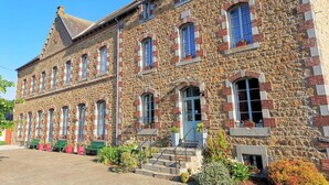 A stone building with multiple windows and a central entrance. - La Récréation - 1 bedroom apartment La Marelle - Covered outdoor swimming pool (Châtelaudren-Plouagat)