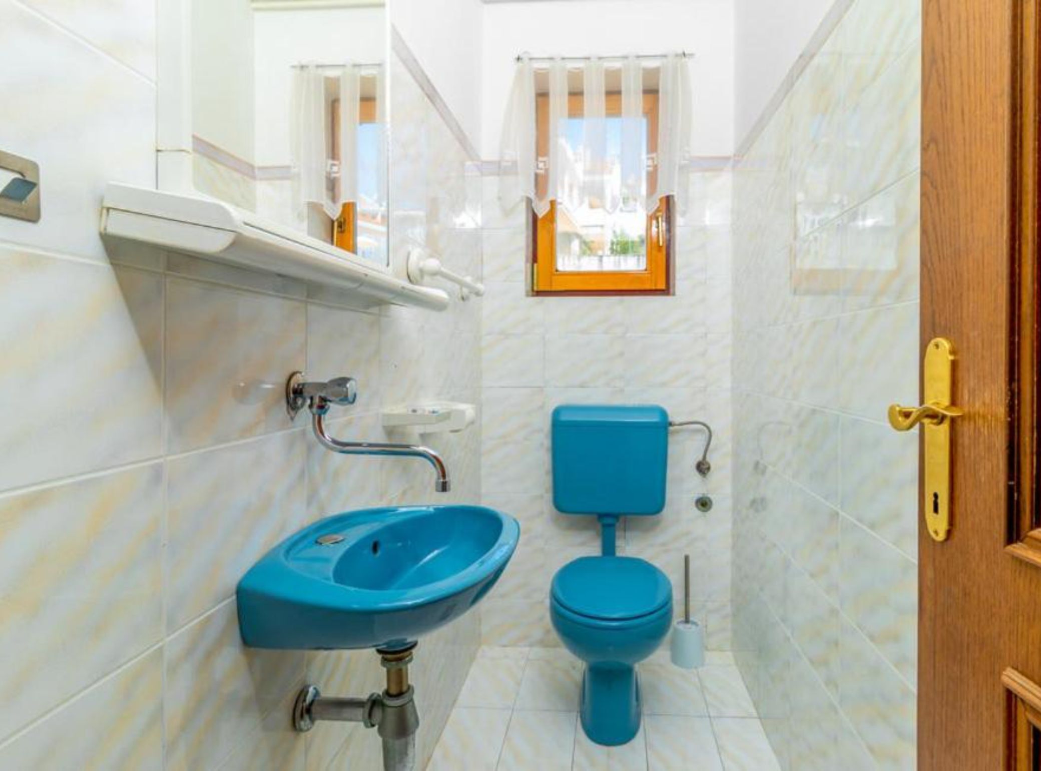 Une salle de bain avec un lavabo, des toilettes et une fenêtre, le tout de couleur bleue.