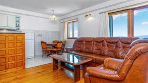 Ein Wohnzimmer mit Ledersofa, Couchtisch aus Holz und Essbereich mit Stühlen und Tisch.