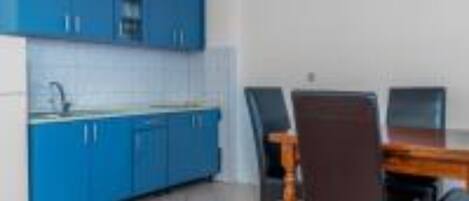 A kitchen with blue cabinets and a dining table with chairs.