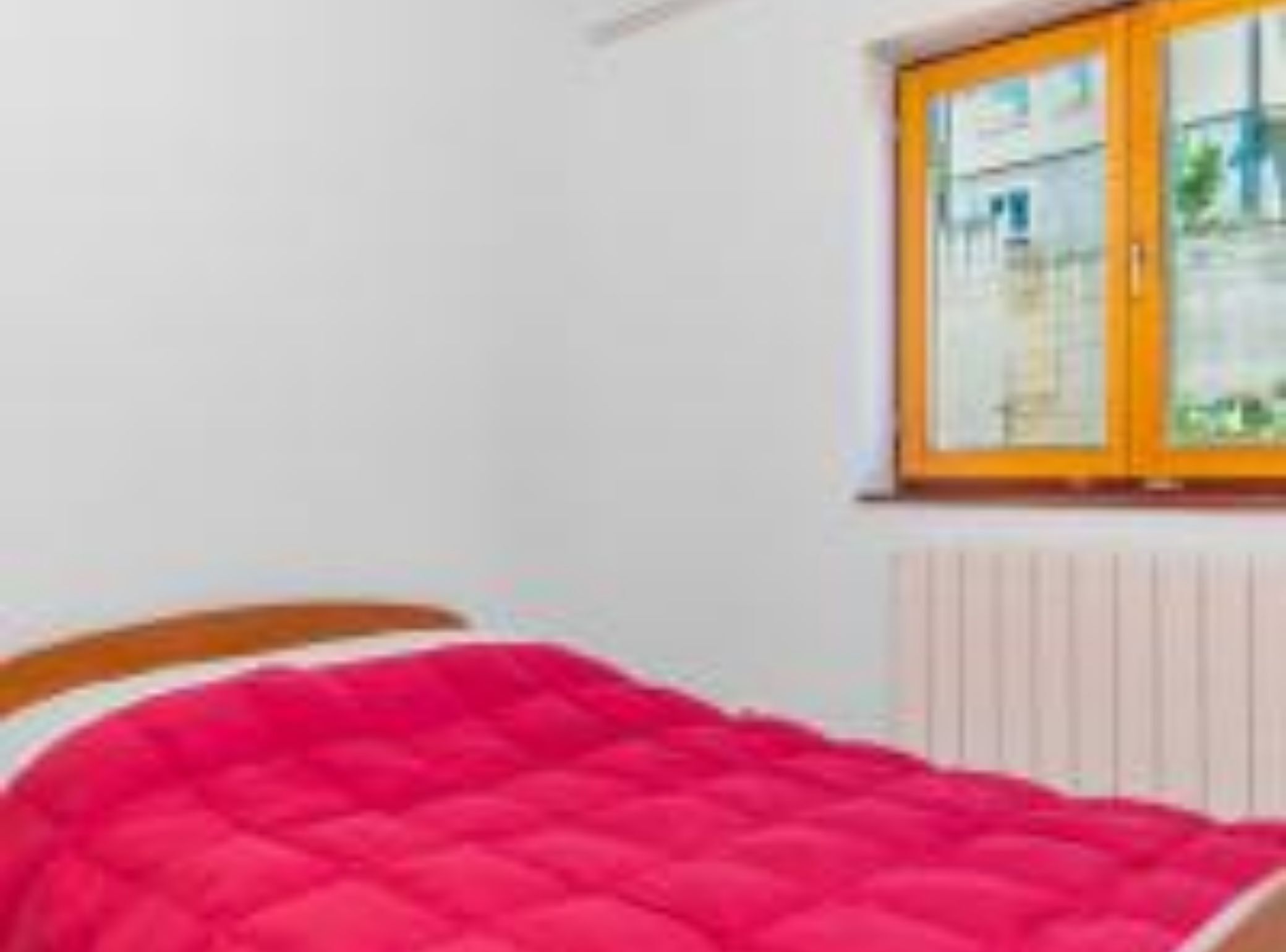 Un dormitorio con una cama, un ventanal y un radiador.