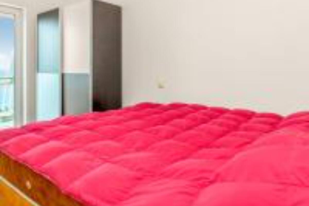 A bedroom with a large bed, a window, and a door.