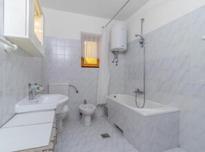 Et lille, moderne badeværelse med vask, toilet, bidet og badekar.