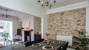 A modern dining area with a long table, chairs, and a decorative wall. - Free Parking | 5 Min to Metro Centre | Modern House (Newcastle Upon Tyne)