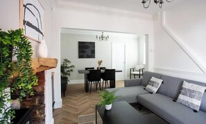 A modern living room with a fireplace, a dining area, and a staircase. - Modern Interior | 5 Mins to Metro Centre | WiFi (Newcastle Upon Tyne)