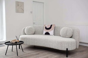 A modern living room with a textured sofa, a round coffee table, and minimalist decor.