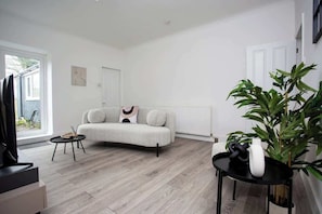 A modern living room with a grey sofa, a small black table, and a potted plant.