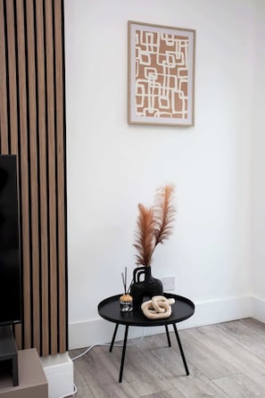 Una sala moderna con una mesa redonda negra, un jarrón decorativo y plumas de pámpano.
