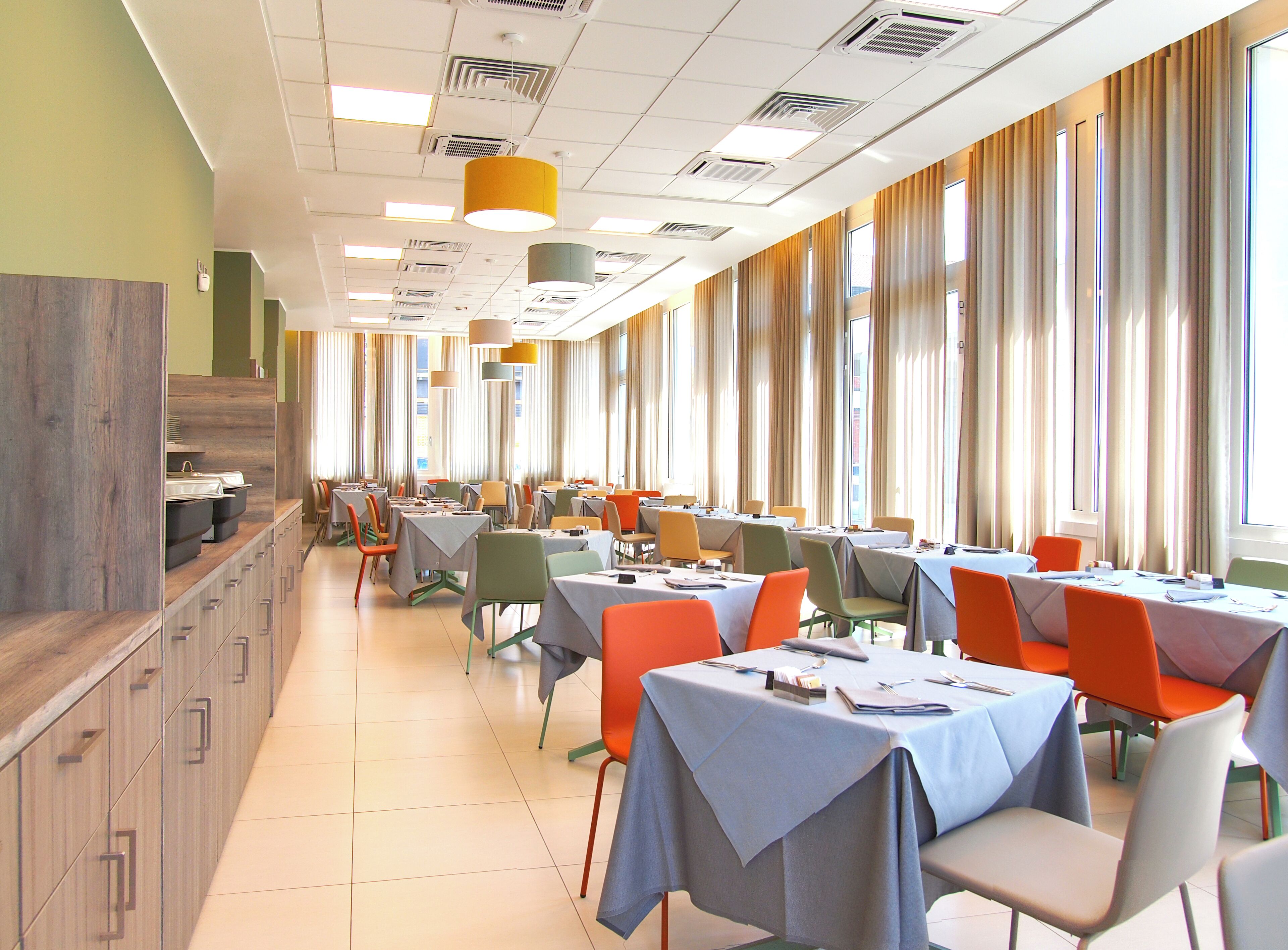 A dining area with tables and chairs, large windows, and a wooden counter.