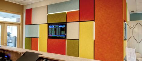 Um balcão de recepção com computador, telefone e painel de exibição digital.