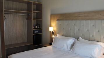 A hotel room with a large bed, a wardrobe, and a nightstand with a lamp.