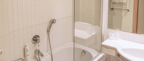 A modern bathroom with a bathtub, shower, and a vanity with a mirror.
