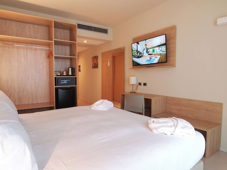 Habitación de hotel con una cama grande, un escritorio, televisión, armario y kitchenette.
