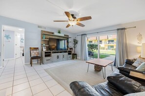 Un salon moderne doté d’un téléviseur à écran plat, d’un canapé en cuir et d’un ventilateur de plafond.