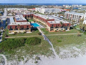 Vue aérienne d’un complexe hôtelier comprenant plusieurs bâtiments, une piscine et une plage.