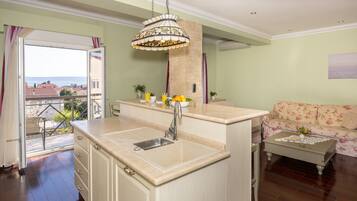A kitchen with a large island, a dining area with a floral sofa, and a view of the outdoors.
