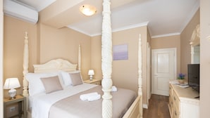 A four-poster bed with a headboard, a bedside table with a lamp, and a dresser with a flat-screen TV. - Villa Vinovo 3 En-suite Bedroom Apartment (Kastela)