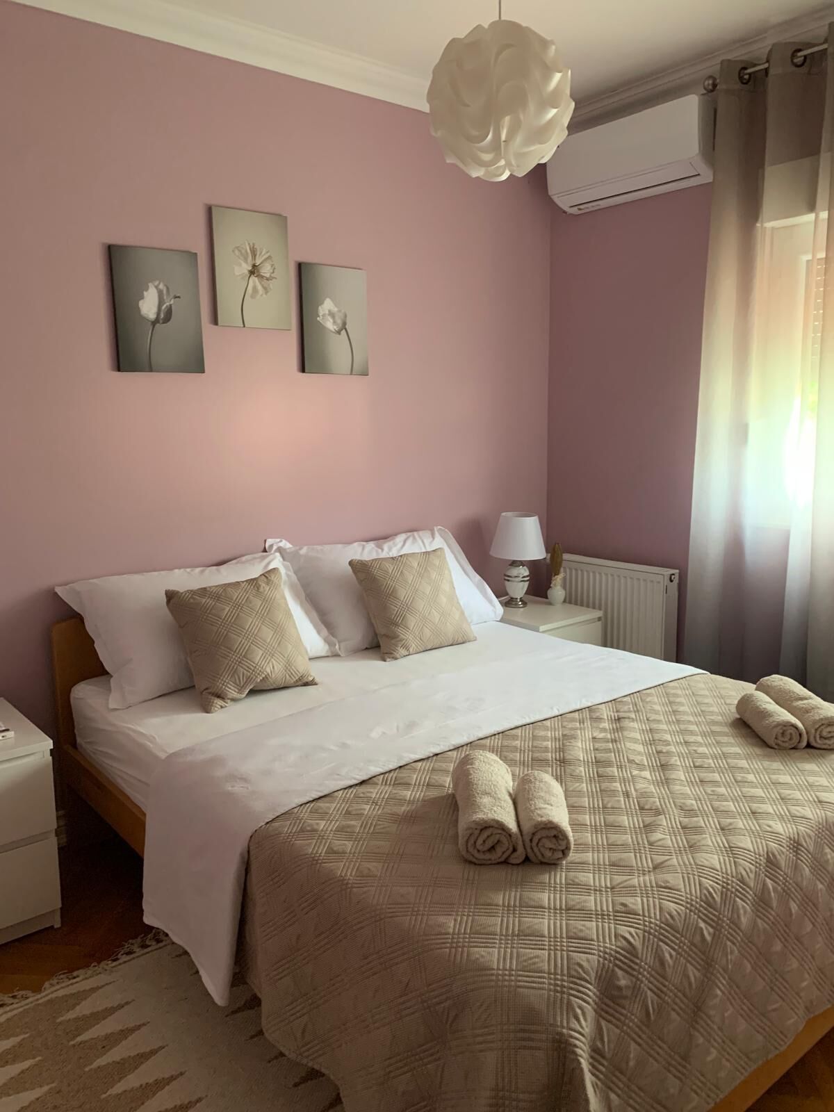 Un dormitorio con una cama grande, una mesita de noche, una lámpara y decoración en la pared.