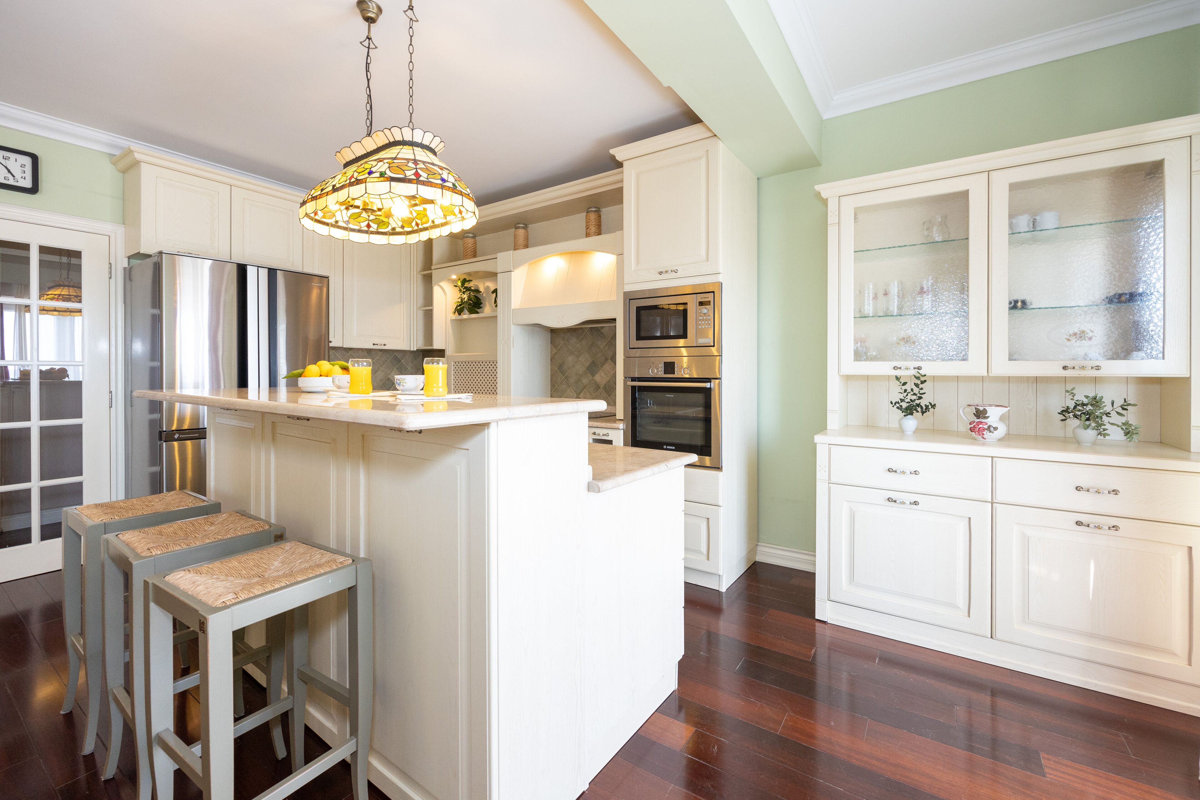 A kitchen with white cabinetry, a central island, stainless steel appliances, and a hanging chandelier.