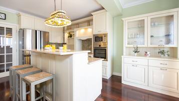 A kitchen with white cabinetry, a central island, stainless steel appliances, and a hanging chandelier.