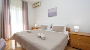 A neatly made bed with rolled towels, a bedside lamp, and a wall-mounted air conditioner. - Double bed Room With Private Bathroom and Balcony (Kastela)
