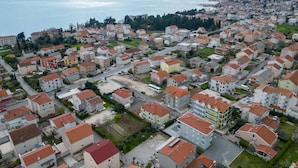 An aerial view of a residential area with uniform housing, a clear view of the sea, and a distant cityscape. - Double bed Room With Private Bathroom and Balcony (Kastela)