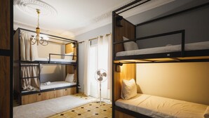 Dormitorio con literas, ventilador, cortinas y un candelabro.