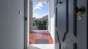 Una puerta que da a un balcón con vistas a edificios y un cielo despejado.