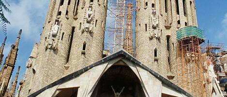 A historic cathedral with two tall towers, a central facade with statues, and scaffolding indicating ongoing restoration.