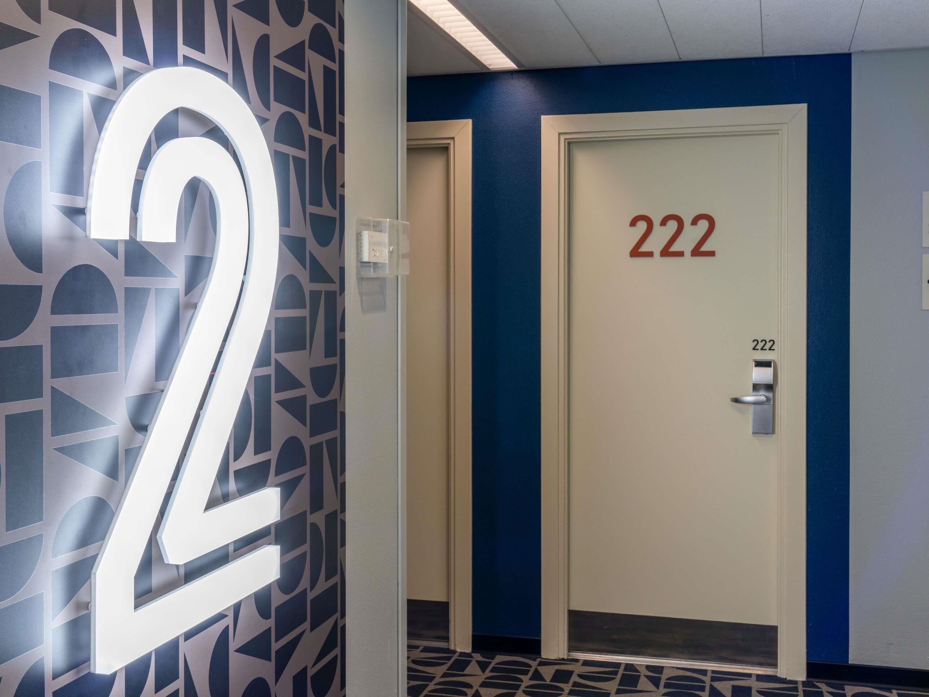 A hallway with a large illuminated number '2' on the wall, a door labeled '222', and a patterned floor.