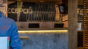 A reception desk with a digital screen, a wall-mounted telephone, and a menu board. - ibis Budget Aeropuerto Barcelona Viladecans (Viladecans)